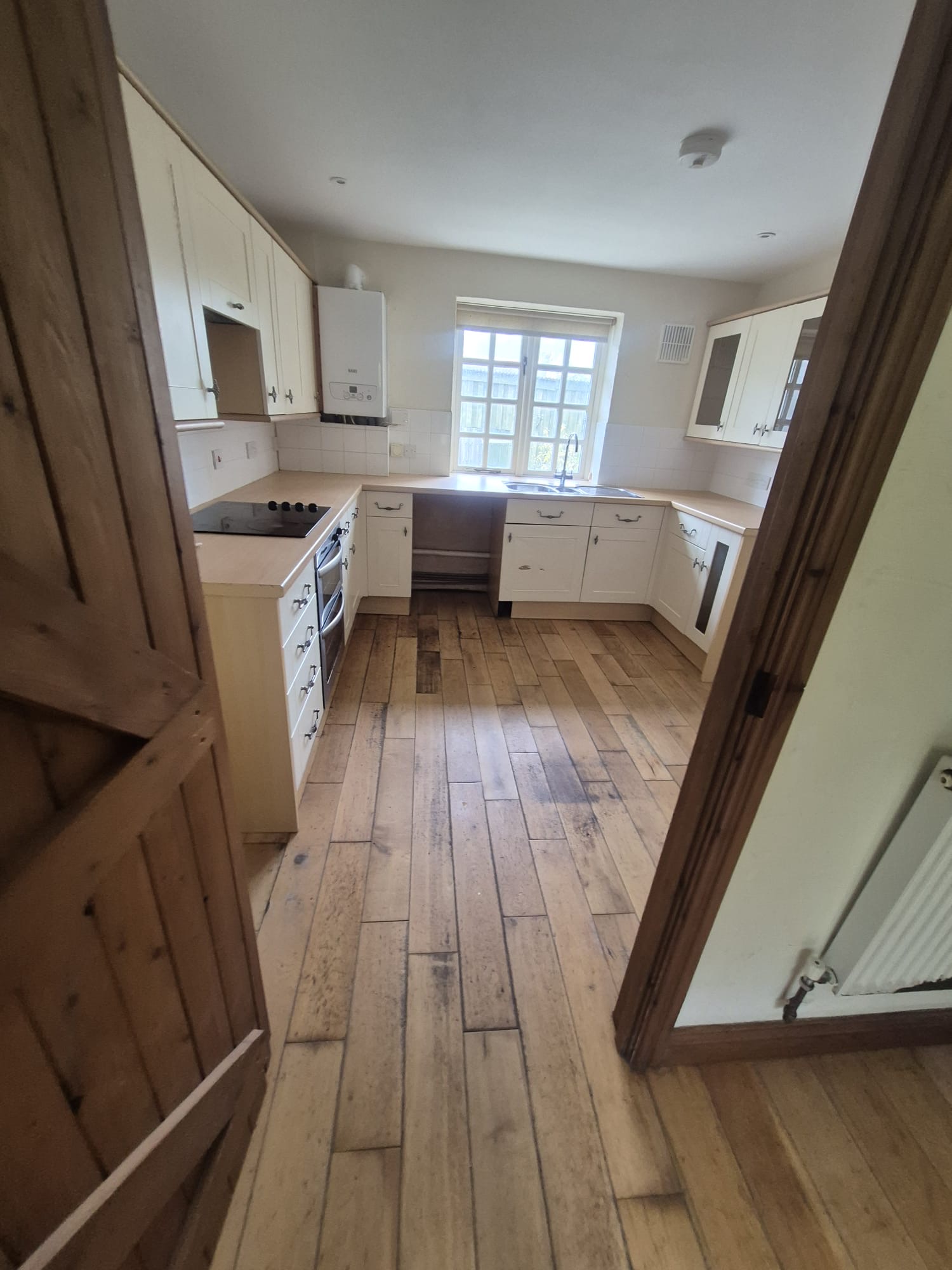 Full kitchen with cream shaker units, hob and window